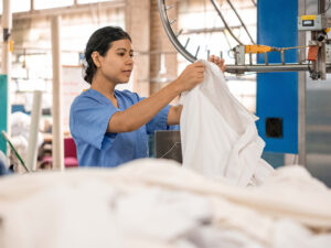 Employee handling hygienically cleaned food service uniforms.